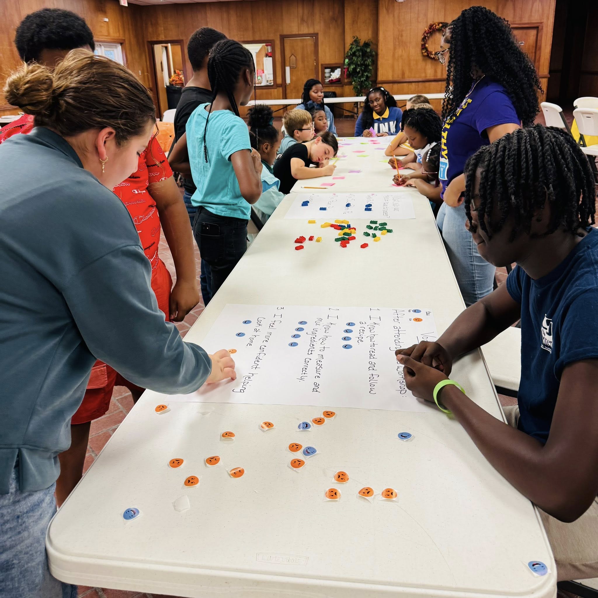 A group of kids reading posters laid on a table.